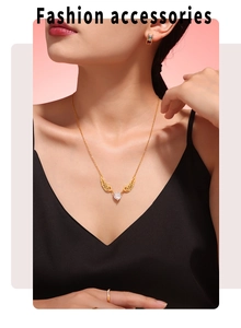 Detailed view of a gold wing and heart zircon pendant necklace on a female model