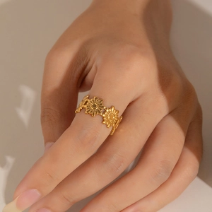 Detailed view of a gold sunflower cutout ring with rhinestones on a female finger
