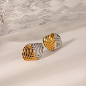 Dettaglio macro di orecchini bicolore oro e argento con trama a strisce verticali e design