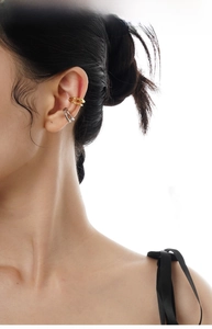 Detailed close-up of gold and silver irregular twisted ear cuffs on ear without piercing