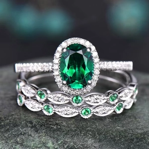 Macro shot of luxury oval green emerald rings with pavé diamonds on textured stone