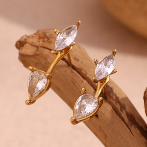 Macro shot of gold-plated pear-cut zircon earrings resting on natural wood background