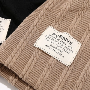 Detail of cable knit beanie with Furnye logo patch in black and camel colors