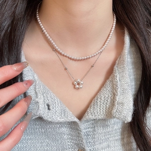 Close-up of elegant double-layered pearl necklace with flower pendant on model