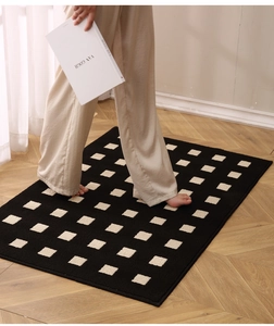 Detail of tufted door mat with black and beige geometric pattern and soft plush texture