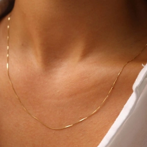 Close-up of minimalist gold thin box chain necklace on model's neck for elegant daily wear