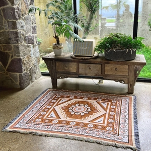 Detail of bohemian geometric woven blanket with fringe on a rustic concrete floor