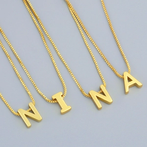 Minimalist gold NINA letter pendant necklace with elegant box chain on grey background