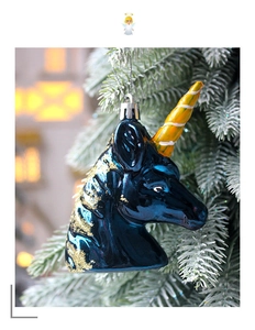 Detail of unicorn head Christmas ornament with gold glitter mane on a festive tree