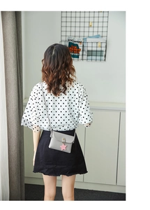Detail of small grey leather crossbody bag with a pink star pendant on a female model