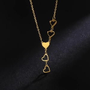 Close-up of golden Y-shaped necklace with heart pendants on a black background