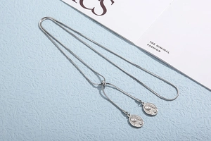 Macro detail of silver snake chain necklace with adjustable clasp and oval Virgin Mary pendants