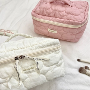 Close-up of pink and white cloud quilted toiletry bags with double zippers and top handle