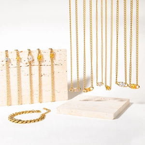 Golden stainless steel jewelry set with necklaces and bracelets on marble stones