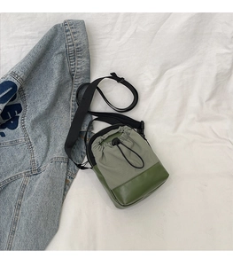 Detail of green fabric crossbody bag with drawstring closure for outdoor hiking