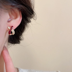 Close-up of red enamel and gold cross earrings with diamonds on model's ear