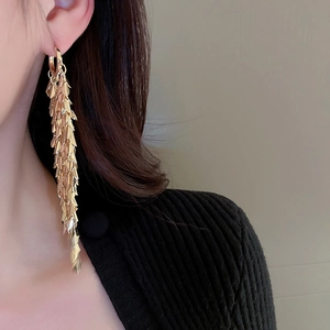 Detailed view of long gold leaf tassel earrings with a heavy metal tiered drop design