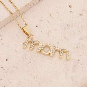Detailed view of gold Mom letter pendant with inlaid cubic zirconia on textured stone