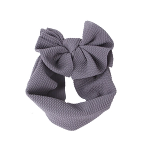 Detail of dark grey waffle knit baby headband with a large bow on a white background