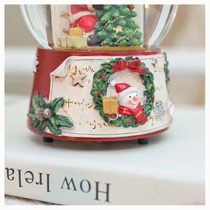 Close-up of Christmas snow globe music box with red resin base and snowman relief