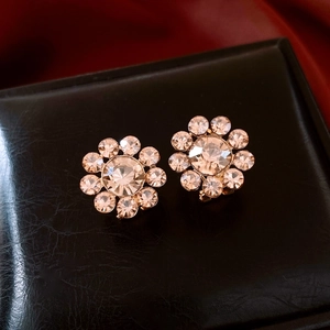 Macro shot of 14K gold plated sunflower earrings with champagne crystals on black leather
