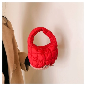Close-up of bright red quilted cloud bag showing soft padded nylon texture and handle