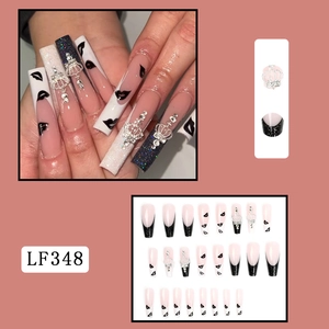 Detail of long coffin press-on nails with black French tips, pink glitter, and silver crown