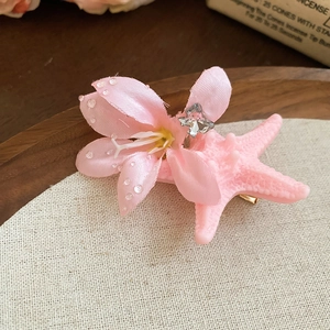 Detailed macro view of a pink starfish hair clip with satin petals and faux diamonds