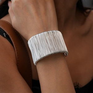 Close-up of wide layered silver-tone geometric line cuff bracelet on a female wrist