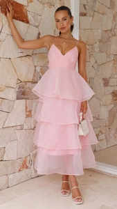 Detail view of pink layered organza ruffles on a backless evening dress against a stone wall