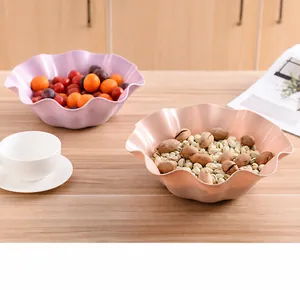 Detail of pink and purple ruffle-edged snack plates on a rustic wooden dining table
