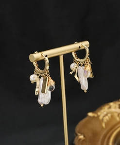 Close-up of golden hook earrings with pearls and crystal on a T-bar jewelry display
