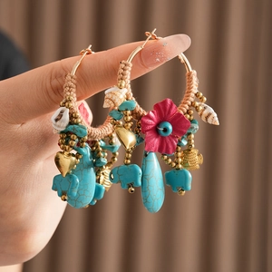 Detail of bohemian earrings with turquoise beads, pink flower, and shell pendants