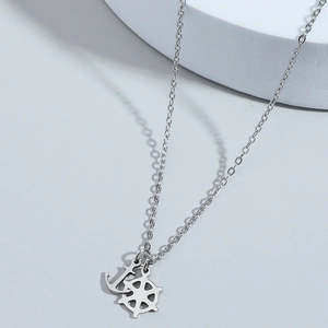 Silver stainless steel nautical necklace with anchor and ship wheel pendants on white podium