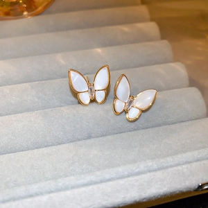 Vue détaillée de boucles d'oreilles papillon avec nacre et cristal sur support velours