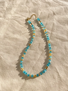 Macro shot of icy blue cat eye stone beads with golden metal tubes and extension chain