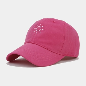 Detail of rose pink cotton baseball cap with intricate white sun embroidery and letters