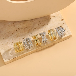 Detailed view of layered gold and silver rings with cubic zirconia on a beige stone surface