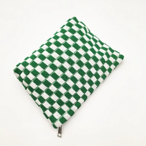 Macro shot of green and white checkered knit fabric texture and durable metal zipper