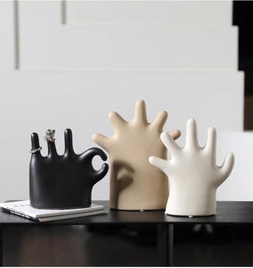 Detailed view of hand-shaped ceramic jewelry holders in black, beige and white colors