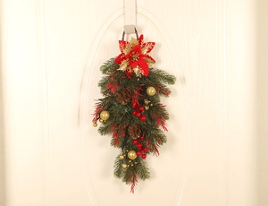 Close-up of Christmas teardrop swag with red poinsettias and gold ornaments on white door