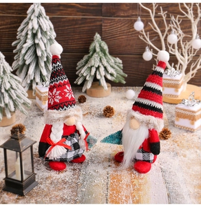 Close-up of adorable Christmas gnomes with striped hats and holiday tree decor