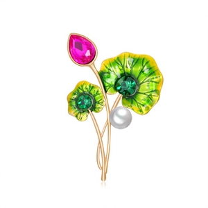 Macro shot of elegant lotus brooch with pink crystals and green enamel on golden metal