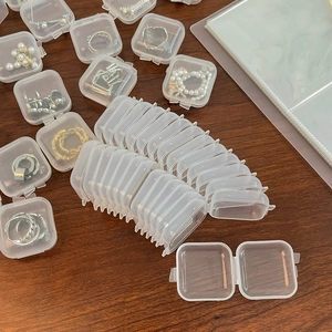 Bovenaanzicht van gestapelde en open transparante plastic juwelendoosjes met ringen