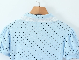 Detail of light blue polka dot romper featuring white lace collar and puff sleeves
