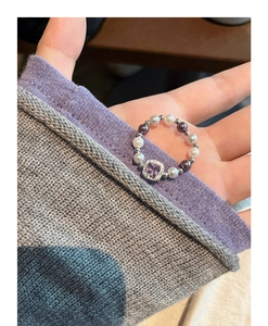 Detailed close-up of elastic pearl ring featuring a square purple gemstone and zircons