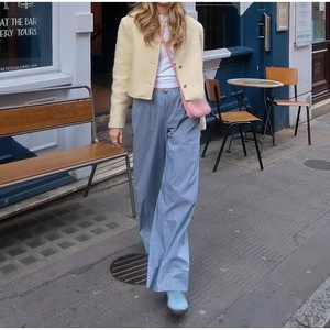 Dettaglio di una giacca di lana beige stile francese abbinata a pantaloni larghi a righe