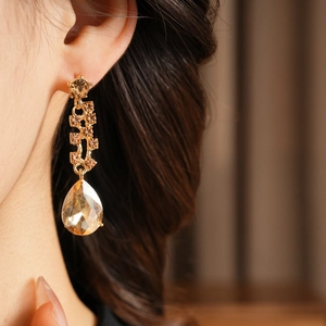 Close-up of model wearing luxury champagne gold teardrop crystal drop earrings