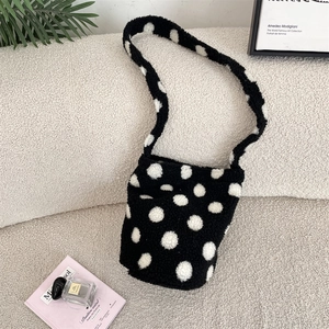 Polka dot plush shoulder bag on a cozy sofa setting with artistic decorative props