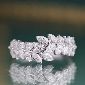 Macro shot of marquise cut gemstones on a silver band with leaf design and reflection
